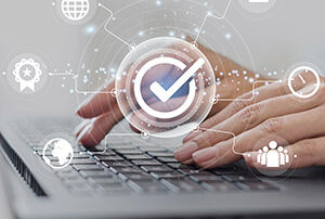 Un gros plan sur des mains qui tapent sur un ordinateur portable, avec des icônes de cybersécurité qui gravitent.