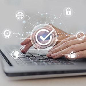 Un gros plan sur des mains qui tapent sur un ordinateur portable, avec des icônes de cybersécurité qui gravitent.